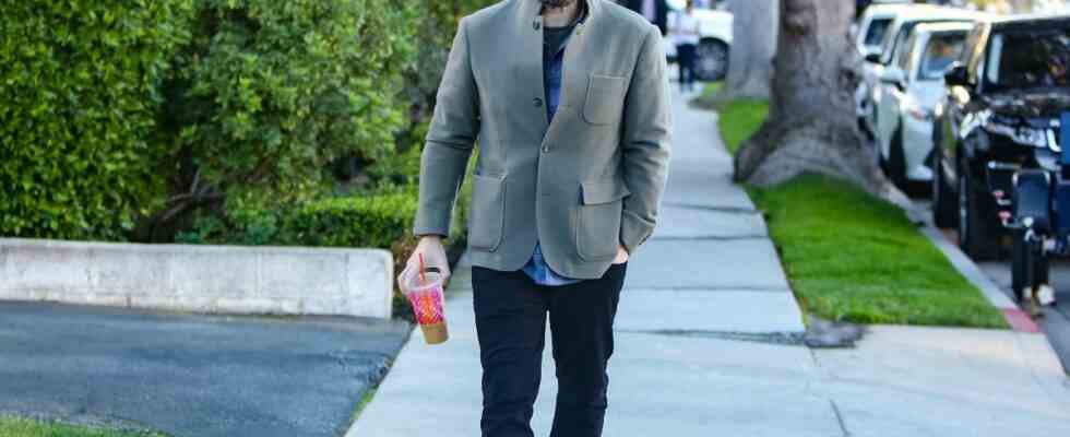 Ben Affleck walking down the street, holding a Dunkin Donuts coffee.