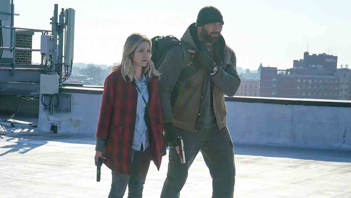 Dave Bautista et Brittany Snow marchent sur un toit par un froid matin new-yorkais et tiennent des pistolets à Bushwick.