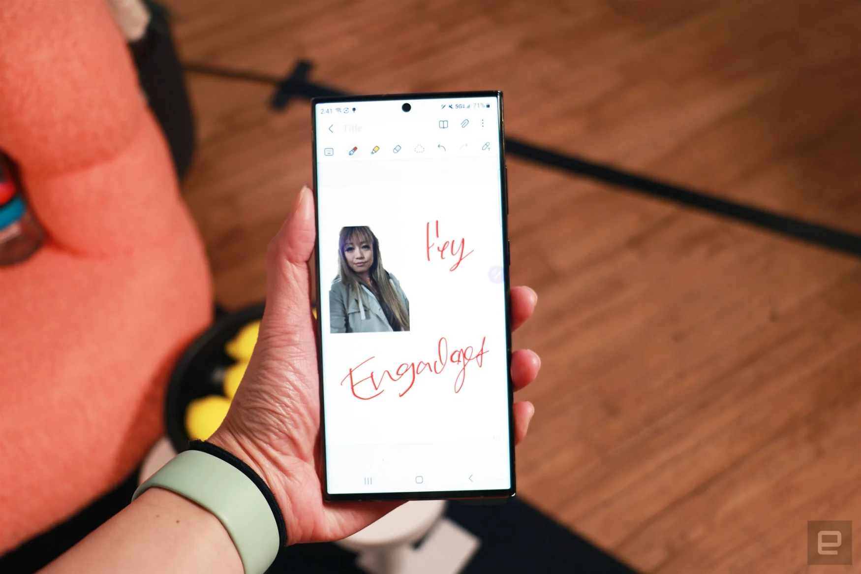 Le Galaxy S23 Ultra tenu dans une main en l'air montrant l'application Samsung Notes.  Sur la toile se trouve une découpe d'une femme en haut à gauche et les mots manuscrits 
