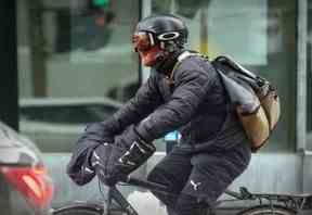 Un messager à vélo couvre son visage contre le vent par une journée extrêmement froide et venteuse à Montréal le vendredi 3 février 2023.