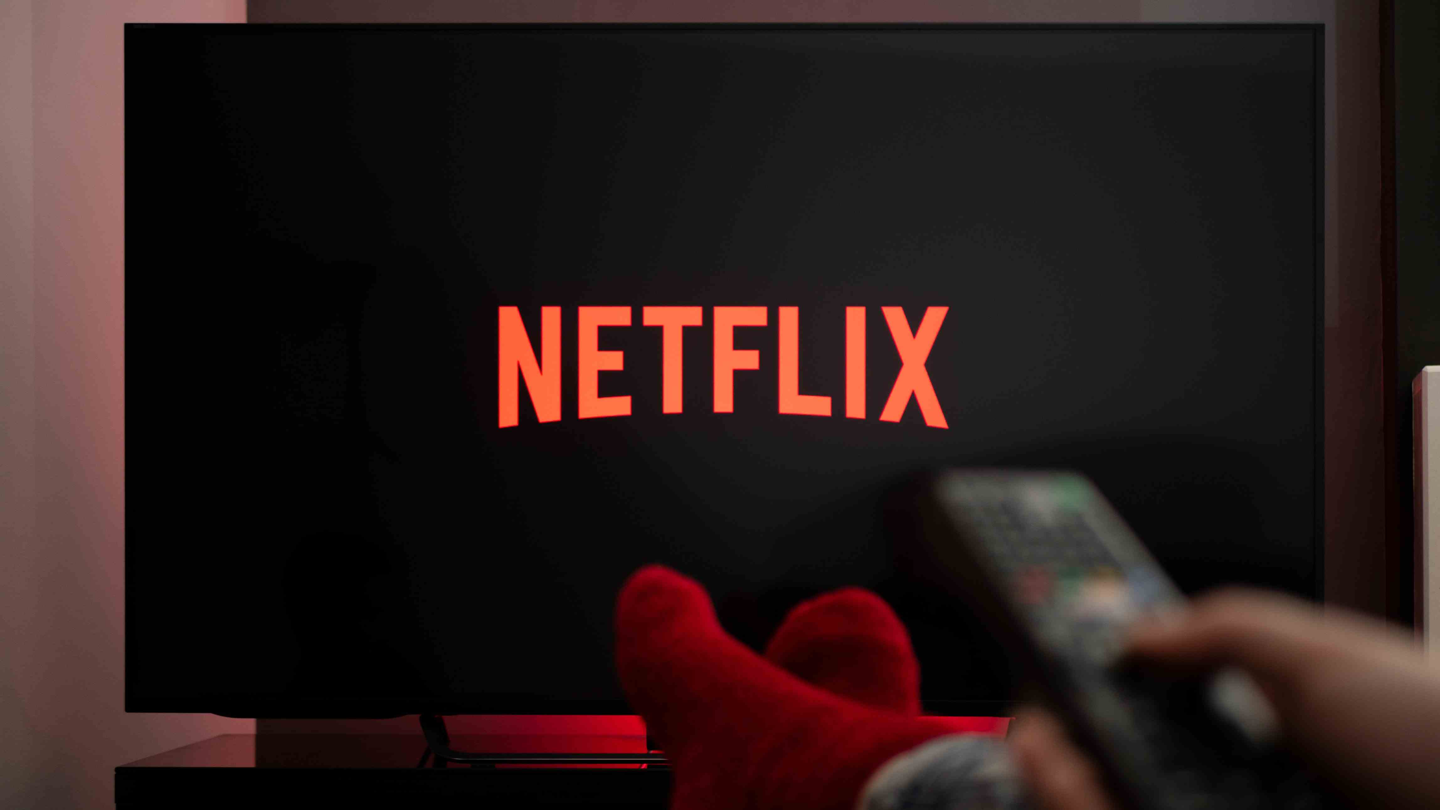 Homme avec ses pieds sur une table tout en regardant Netflix à la télévision