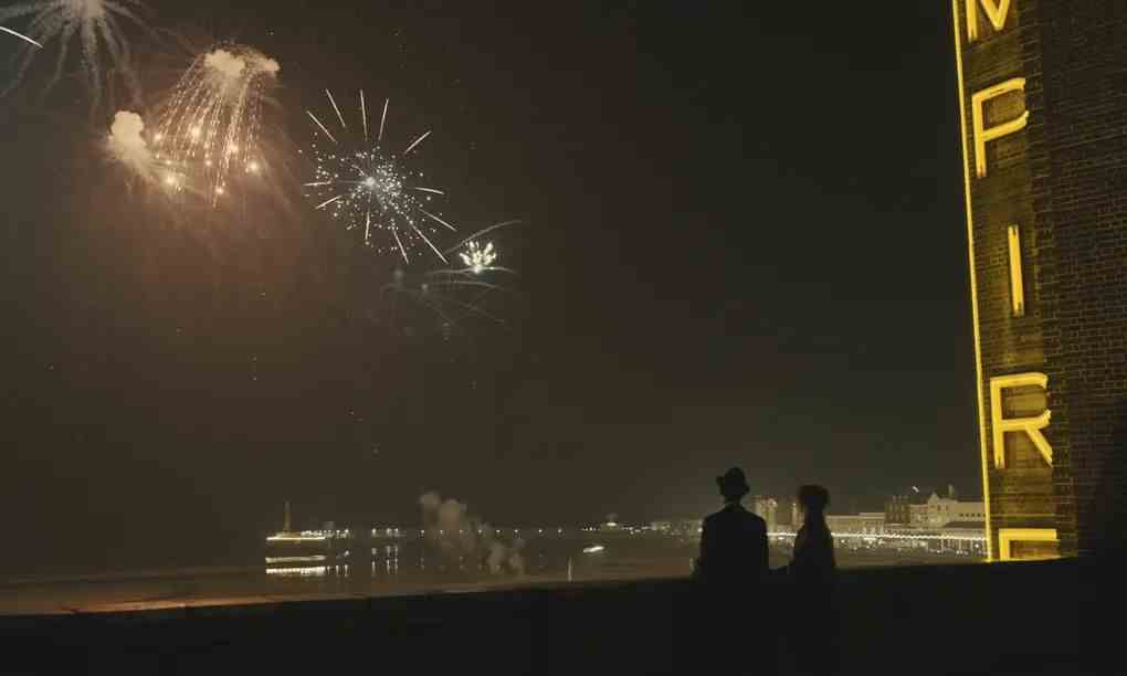 Deux personnes regardent des feux d'artifice dans le ciel à côté d'un chapiteau de cinéma qui dit 
