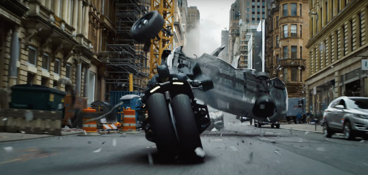 Batman s'éloigne rapidement d'une voiture de police qui tombe sur sa moto dans The Flash. 