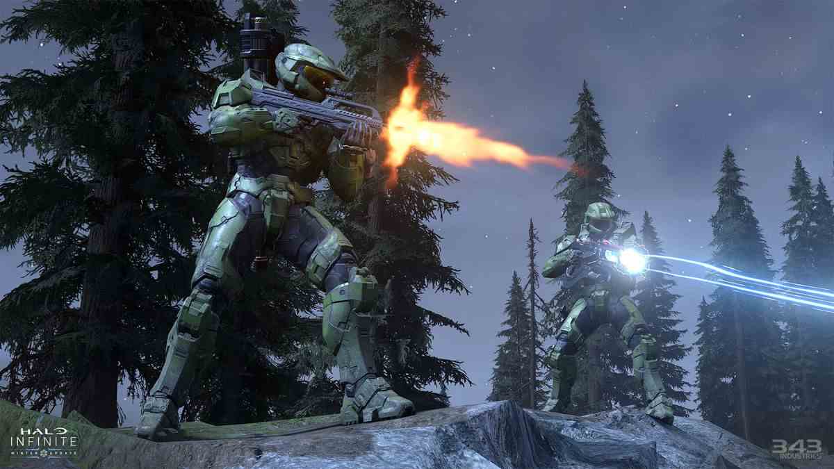Master Chief et un autre Spartan tirent des armes depuis un rocher, avec des arbres derrière, dans Halo Infinite