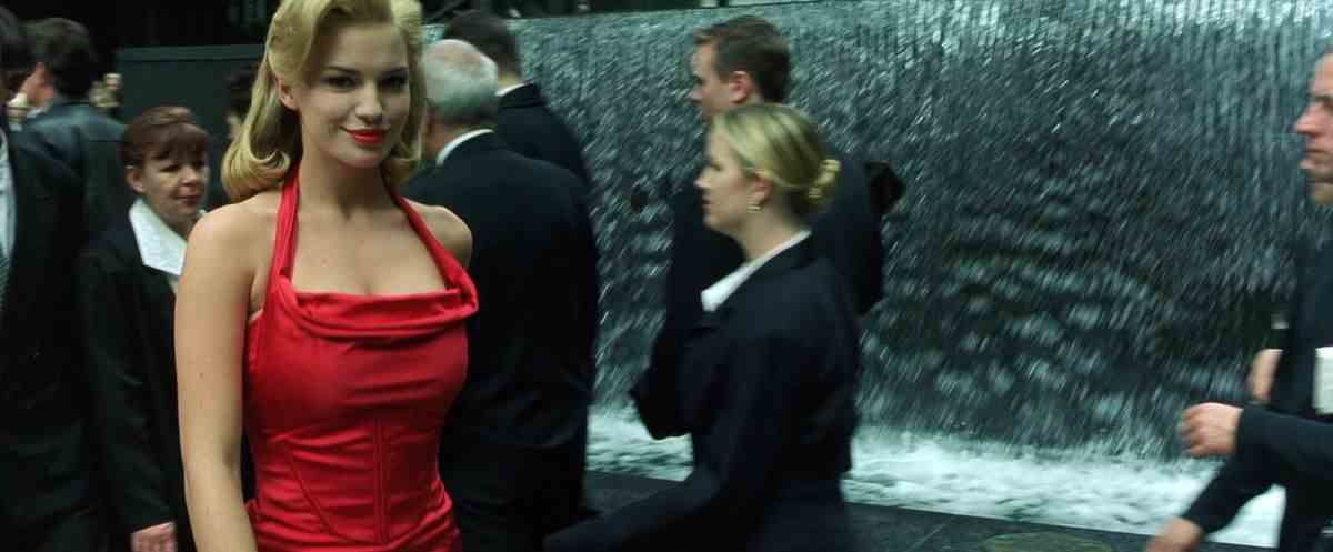 Fiona Johnson sourit en regardant la caméra et en portant une robe rouge dans The Matrix