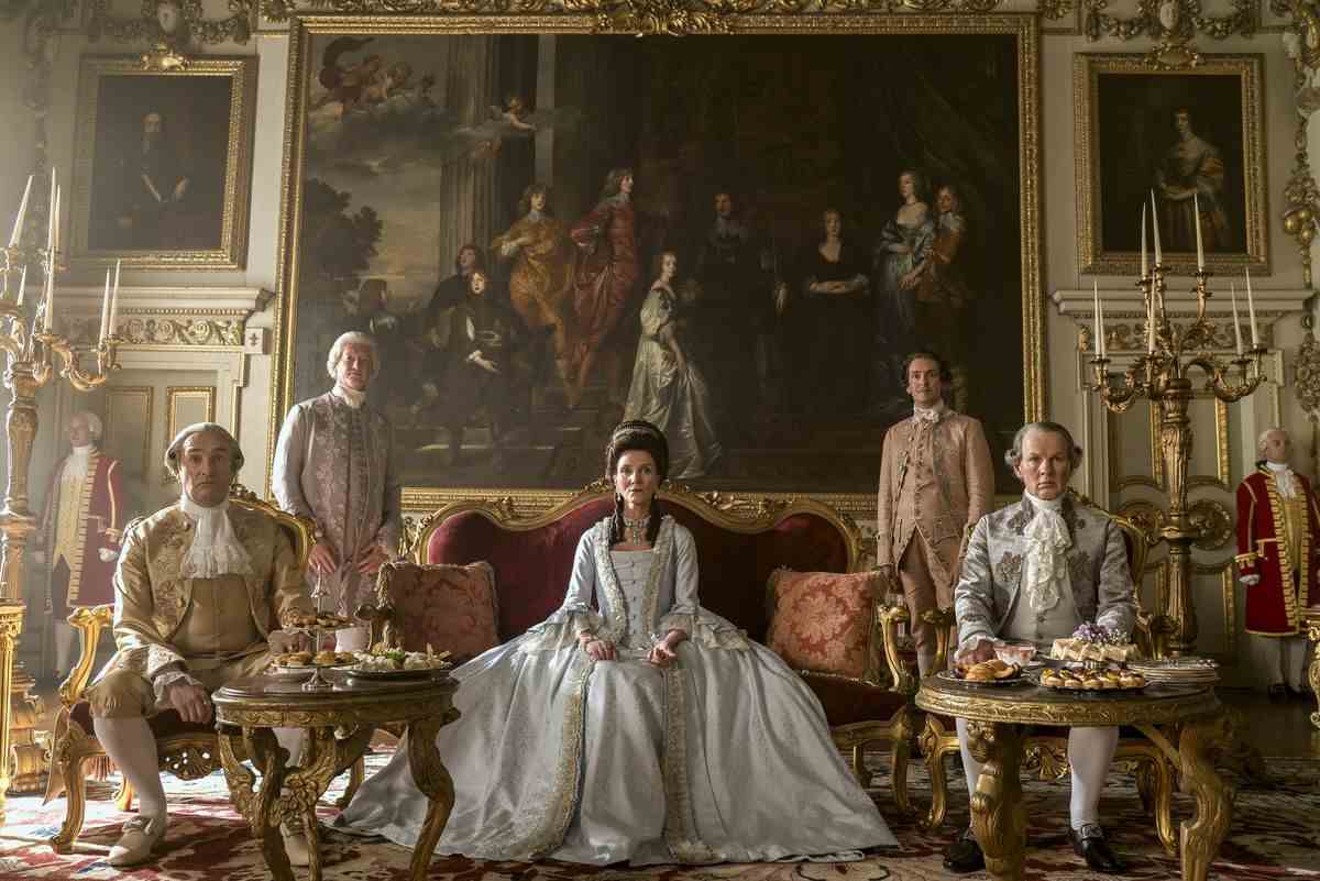 un groupe de noblesse de fantaisie posant dans une salle à manger extravagante, une femme avec une grande robe au centre