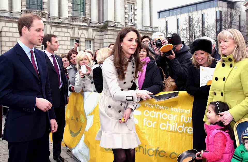 Le prince William regarde Kate Middleton retourner une crêpe lors d'un événement du Northern Ireland Cancer Fund for Children devant l'hôtel de ville de Belfast, lors de leur visite en Irlande du Nord.  (Photo de Paul Faith/PA Images via Getty Images)