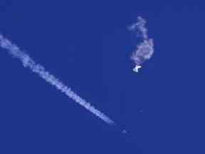 Les restes d'un grand ballon dérivent au-dessus de l'océan Atlantique, juste au large de la Caroline du Sud, avec un avion de chasse et sa traînée vue en dessous, le 4 février 2023.