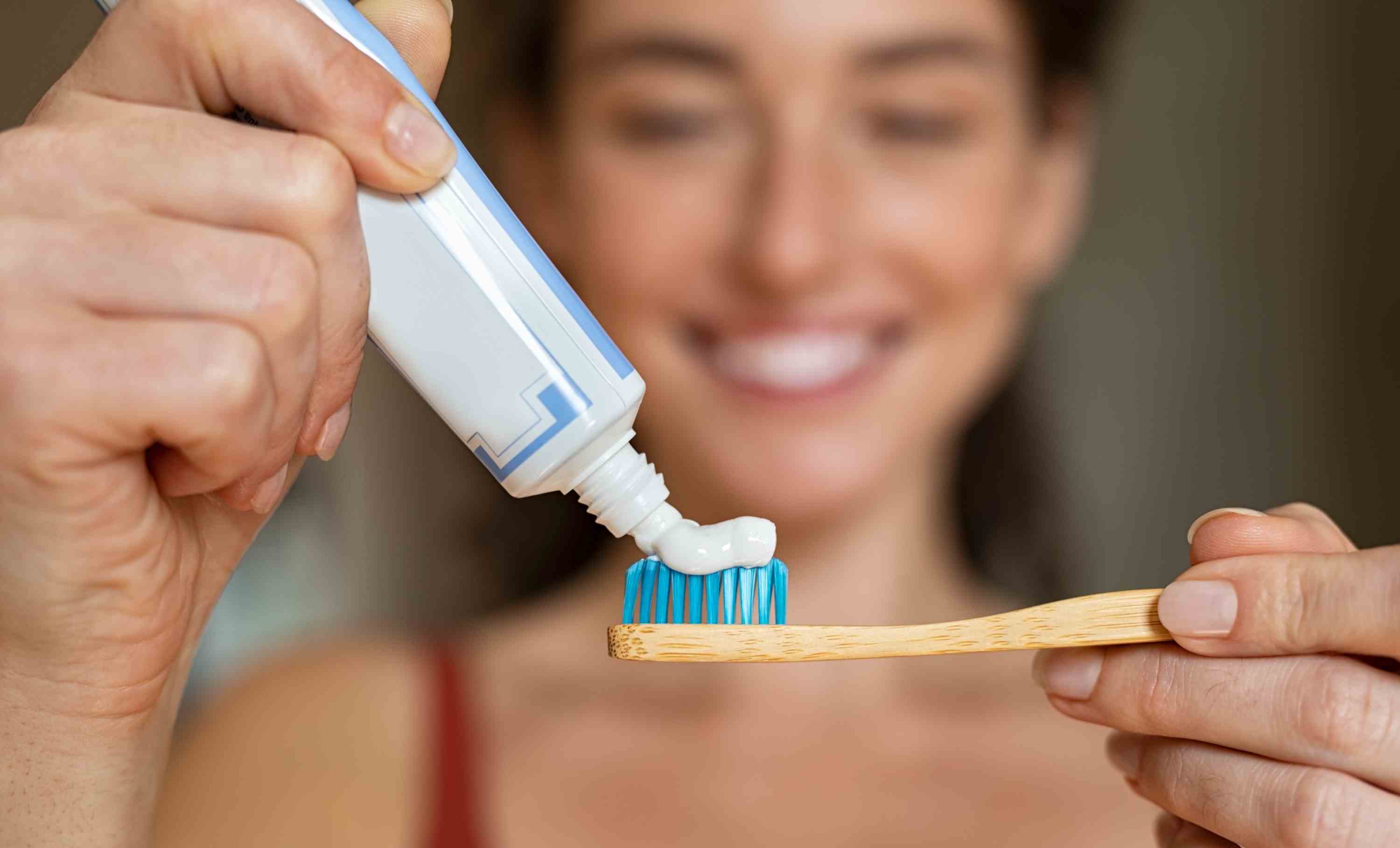 femme mettant du dentifrice sur une brosse à dents