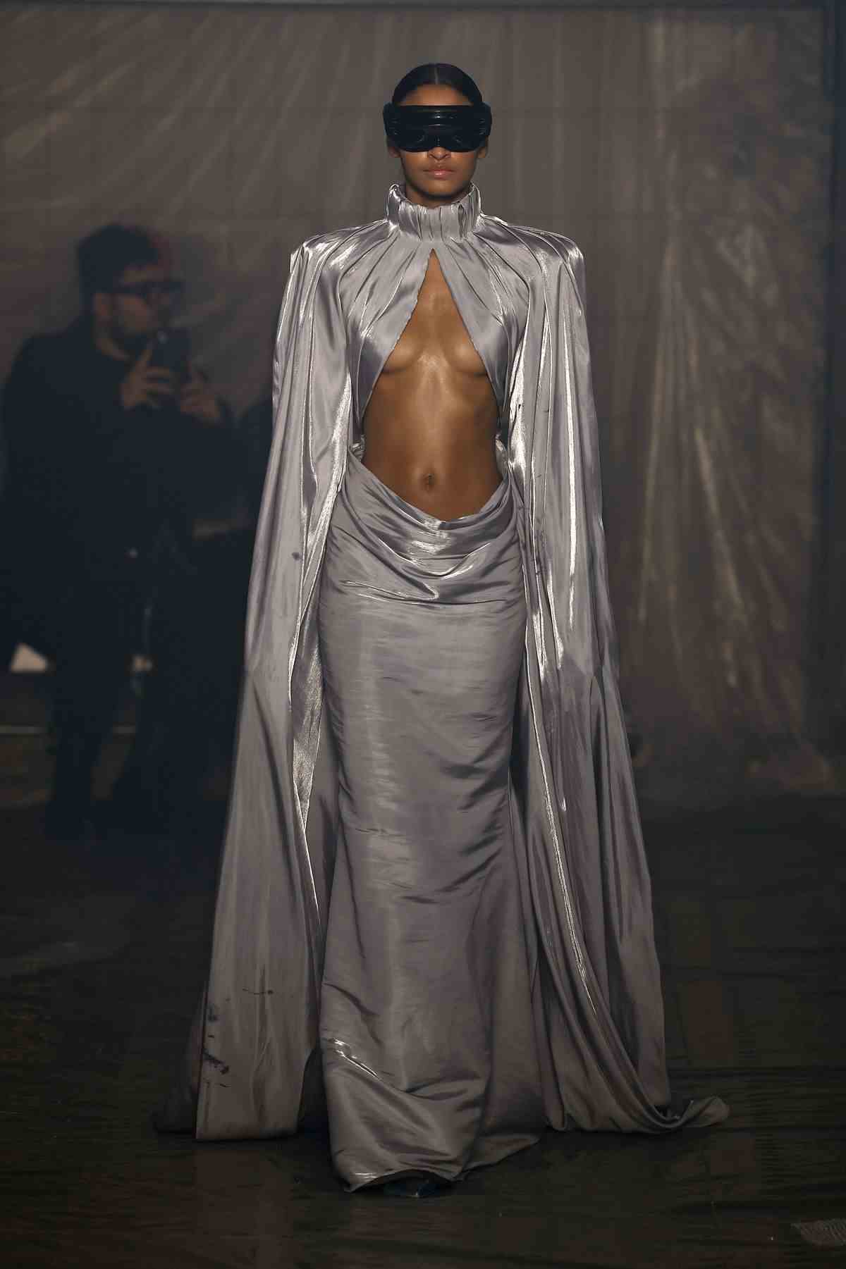 Un mannequin portant une robe grise fluide avec son ventre exposé parcourt la piste du défilé de mode Han Kjobenhavn à la Fashion Week de Milan.