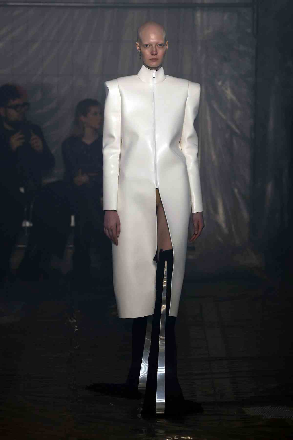 Un mannequin portant un long manteau en cuir blanc et des talons avec des protubérances en forme d'épée défile sur la piste du défilé de mode Han Kjobenhavn à la Fashion Week de Milan.