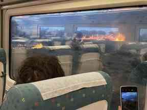 Des passagers prennent des photos d'un feu de forêt alors qu'ils voyagent dans un train à Zamora, en Espagne, le lundi 18 juillet 2022. Fichiers.