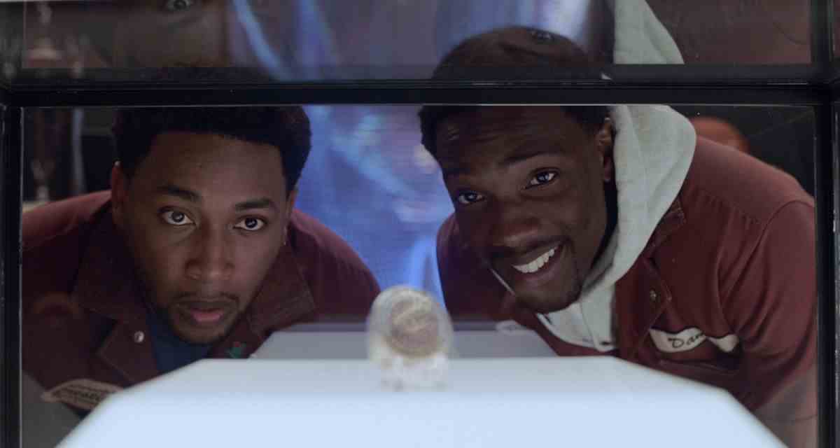Les deux stars de House Party regardent l'une des bagues de championnat de LeBron James dans une vitrine dans House Party.