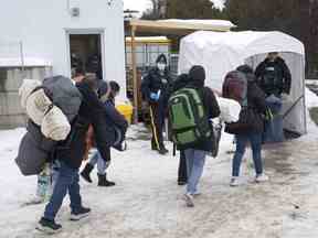 Une famille de demandeurs d'asile de Columbia est accueillie par des agents de la GRC après avoir traversé la frontière à Roxham Road vers le Canada le jeudi 9 février 2023 à Champlain, NY