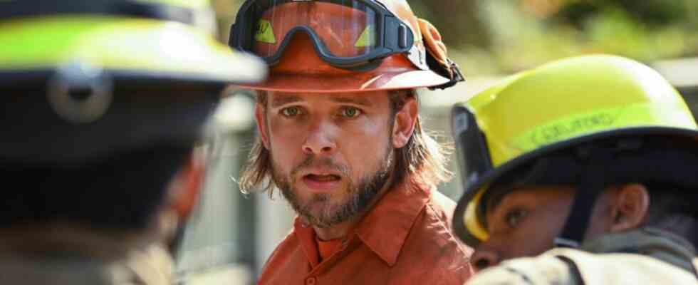 Max Thieriot looking into the distance with two other firefighters in the foreground on Fire Country.