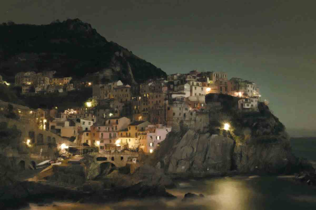 Un village italien à flanc de falaise.  Il fait nuit et la lumière jaune projette d'étranges ombres sur la terre.