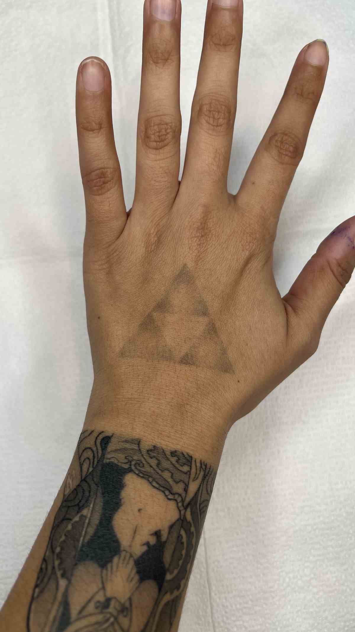 Un léger tatouage Triforce sur la main d'une personne
