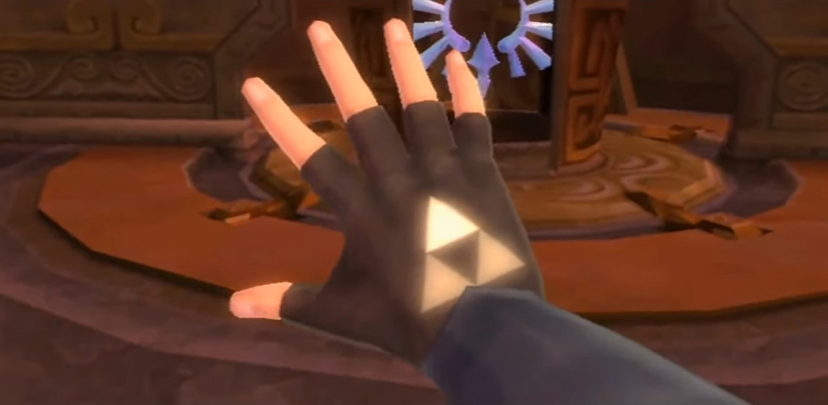 Un gros plan de la main de Link dans The Legend of Zelda: Skyward Sword.  Les trois triangles qui composent la Triforce brillent à travers son gant, le triangle supérieur étant le plus brillant.