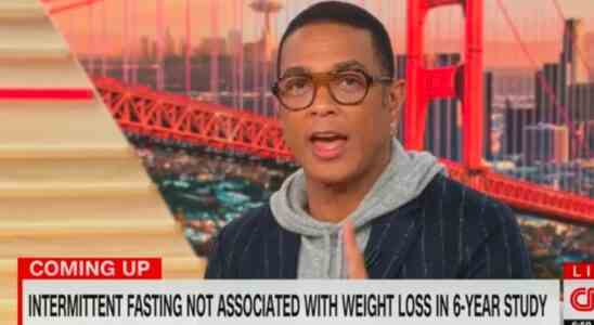 Don Lemon reading the news in a hooded and a suit coat.
