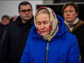 Une femme réagit lors d'un service de prière à l'église Saint-André de Bucha, près de Kiev, le 24 février 2023, à l'occasion du premier anniversaire de l'invasion russe de l'Ukraine.