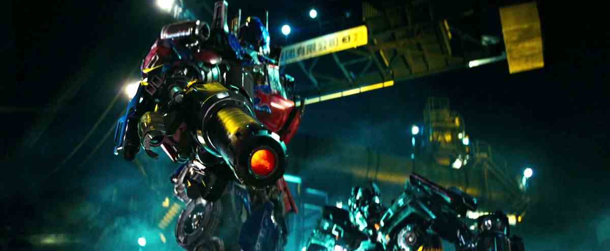 Optimus Prime tient une arme à feu et appuie sur la gâchette tandis qu'un autre Transformer regarde Revenge of the Fallen