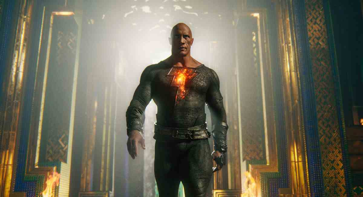 Dwayne Johnson se dirige vers la caméra dans un costume noir moulant avec un éclair brillant sur la poitrine en tant que personnage principal de Black Adam