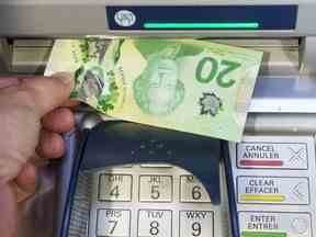 L'argent est retiré d'un guichet automatique à Montréal, le 30 mai 2016. Un nouveau sondage révèle qu'un tiers des ménages canadiens affirment que leur situation financière s'est détériorée au cours de la dernière année.
