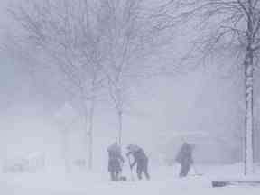 Les gens pelletent leurs allées dans une tempête de neige à Mississauga, en Ontario, le mercredi 25 janvier 2023.