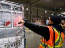 Un employé de FedEx scanne une cargaison transportant 255 600 doses du vaccin Moderna COVID-19 à l'aéroport international Pearson de Toronto le 24 mars 2021.