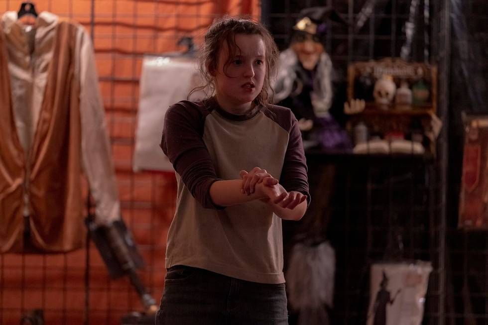 Ellie (Bella Ramsey) debout et ayant l'air effrayée alors qu'elle serre son bras 
