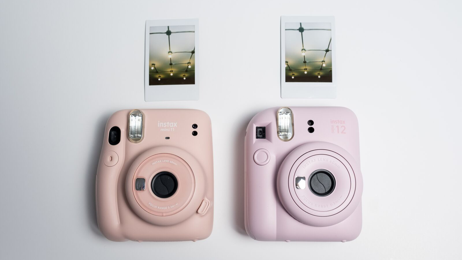 Fujifilm Instax Mini 12 aux côtés d'Instax Mini 11 avec des impressions instantanées de chaque appareil photo sur fond blanc