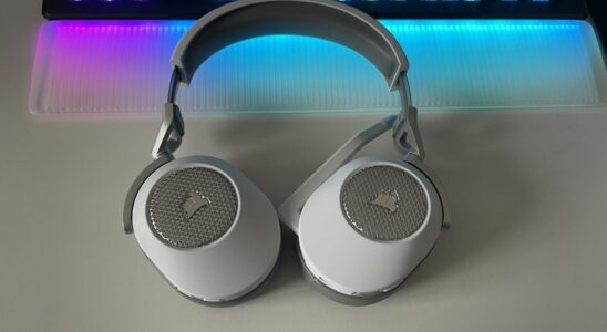 Corsair HS65 Wireless gaming headset sitting on a desk with RGB lighting