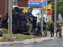 Des agents d'intervention d'urgence entrent dans une résidence à Moncton, au Nouveau-Brunswick, le 5 juin 2014. Trois agents de la GRC ont été tués et deux blessés par un homme armé portant un camouflage militaire et brandissant deux armes à feu.