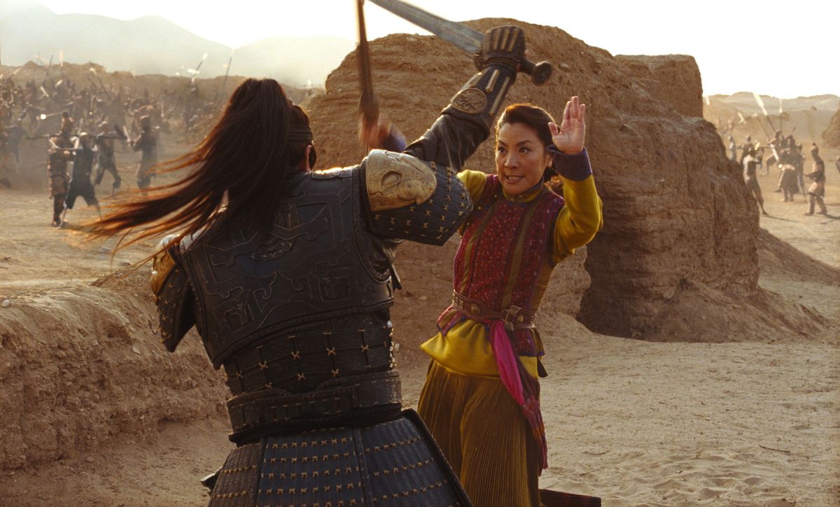 Michelle Yeoh dans The Mummy: Tomb of the Dragon Emperor épée combattant un ancien guerrier en armure cloutée dans un décor désertique