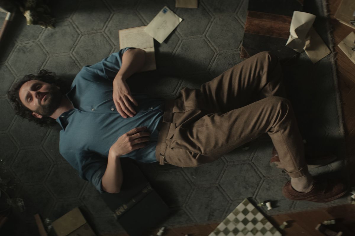 Joe Goldberg est allongé sur le sol de son appartement avec des livres, des papiers et un échiquier autour de lui dans You saison 4.