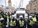 La police suspend un camion alors que les autorités s'efforcent de mettre fin à une manifestation contre les mesures COVID-19 qui s'était transformée en une manifestation antigouvernementale plus large et une occupation qui a duré des semaines, à Ottawa, le samedi 19 février 2022.