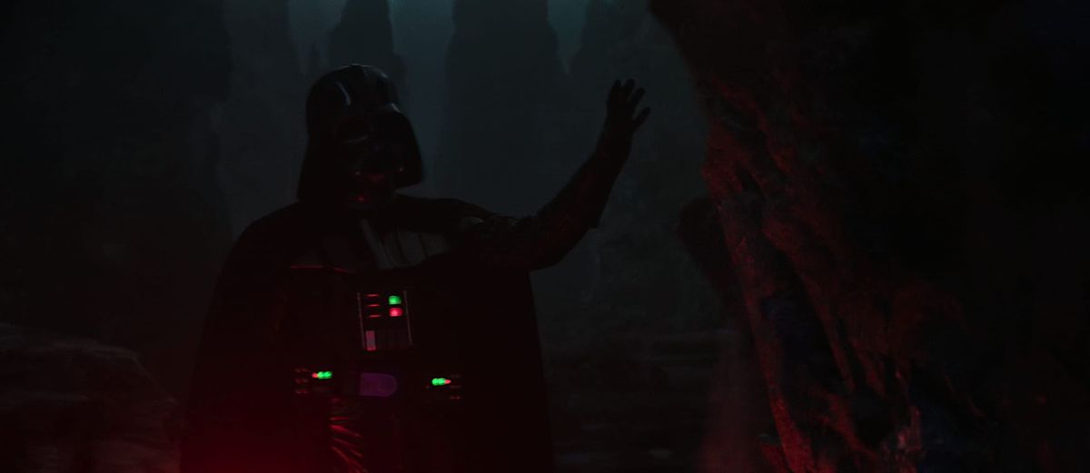 À peine visible dans l'obscurité, Dark Vador lève la main pour utiliser la Force pour effondrer une flèche de pierre au-dessus d'Obi-Wan Kenobi lors de leur combat dans la série Obi-Wan Kenobi de Disney Plus.