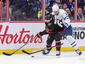Le défenseur des Maple Leafs Luke Schenn perd son bâton alors qu'il se bat avec l'attaquant des Sénateurs Derick Brassard derrière le filet en première période.