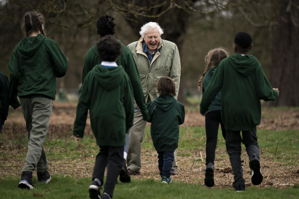 Sir David Attenborough avec des écoliers alors qu'il plante l'arbre à Richmond Park