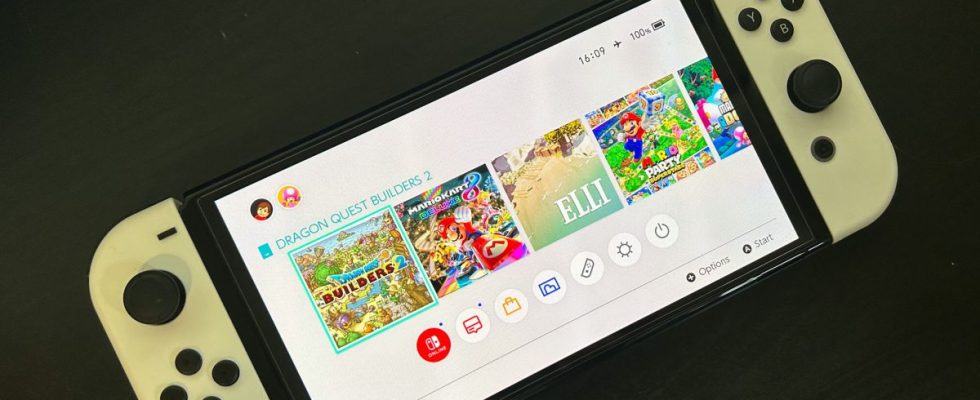 Nintendo Switch console on black table, on to show homescreen with games and battery level indicator