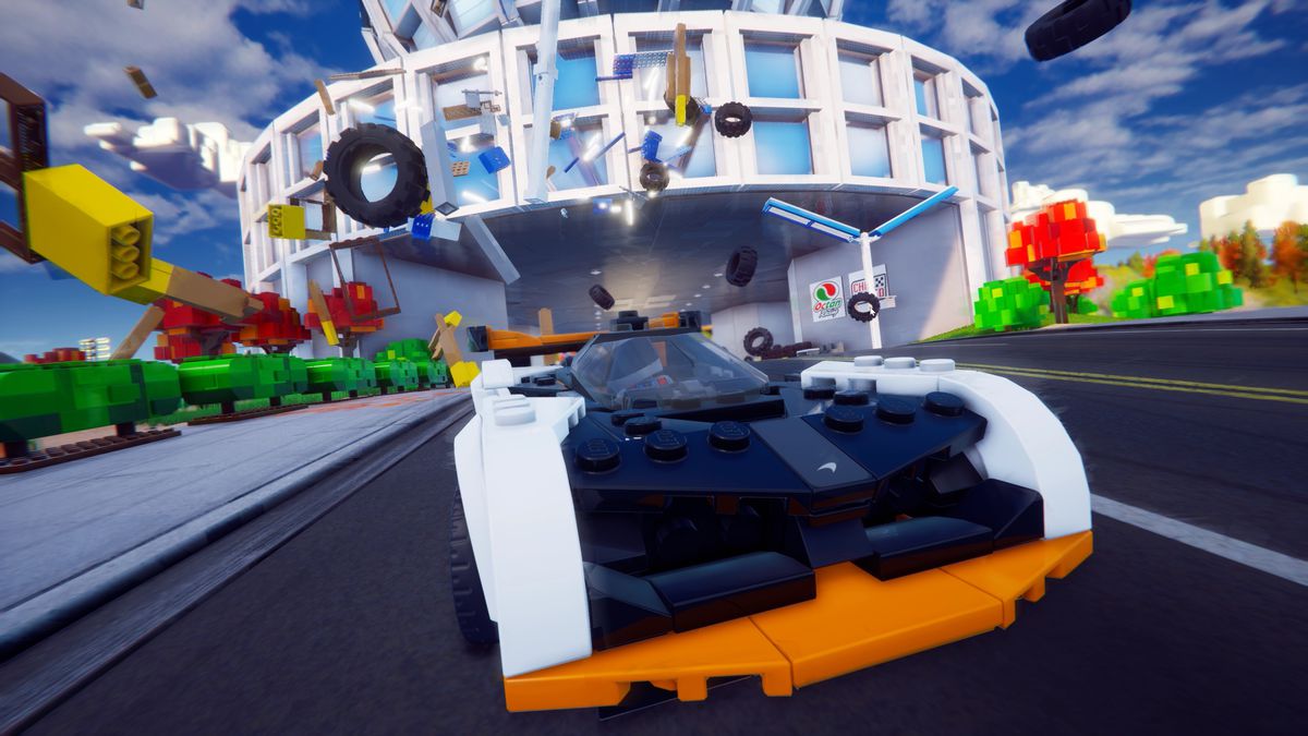 Une capture d'écran de Lego 2K Drive, montrant une voiture de course traversant une construction Lego et pulvérisant des briques et des pneus partout