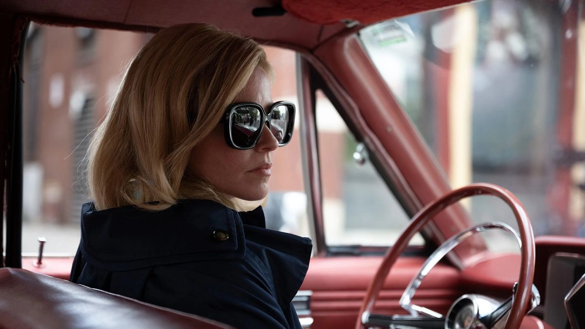 Une femme (Elizabeth Banks) portant des lunettes de soleil et assise au volant d'une décapotable rouge dans Call Jane