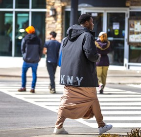 Un demandeur d'asile d'Afrique, l'un des milliers de migrants séjournant dans des hôtels à Niagara Falls, en Ontario, en promenade le vendredi 24 mars 2023.