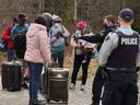 Des demandeurs d'asile parlent à un policier alors qu'ils entrent au Canada depuis la frontière américaine, près d'un point de contrôle sur Roxham Road le 24 avril 2022.