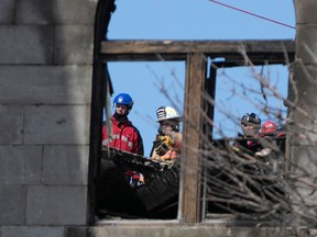 Les pompiers de Montréal et les membres d'une équipe de démolition se consultent le mercredi 22 mars 2023 sur les lieux de l'incendie de la semaine dernière dans le Vieux-Montréal.
