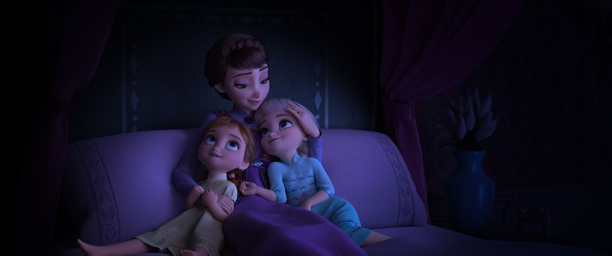 La reine Iduna, une femme brune pâle câline ses deux filles, Anna et Elsa