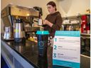 Signalisation sur le programme de partage de tasses au Continental Coffee House tandis que la barista Elli Beatty prépare une boisson.