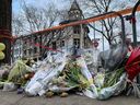 Des fleurs se sont déposées près de la scène de l'incendie du Vieux-Montréal le 28 mars 2023. Les corps des sept personnes disparues ont été récupérés de l'immeuble en arrière-plan et l'enquête sur la cause de l'incendie va commencer.