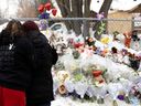 Deux femmes se réconfortent alors qu'elles visitent le site de l'accident mortel d'autobus à la Garderie Éducative Ste-Rose à Laval le jeudi 9 février 2023.