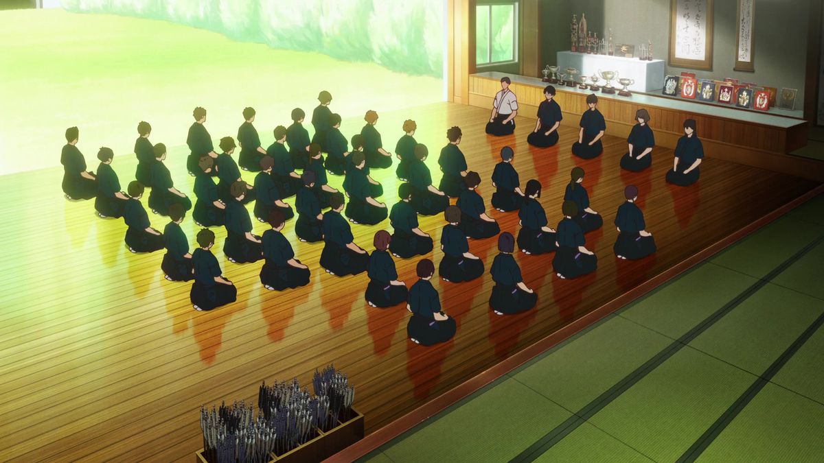Un groupe d'élèves de Kyudo assis au garde-à-vous dans une salle de tir à l'arc devant un groupe de cinq instructeurs.
